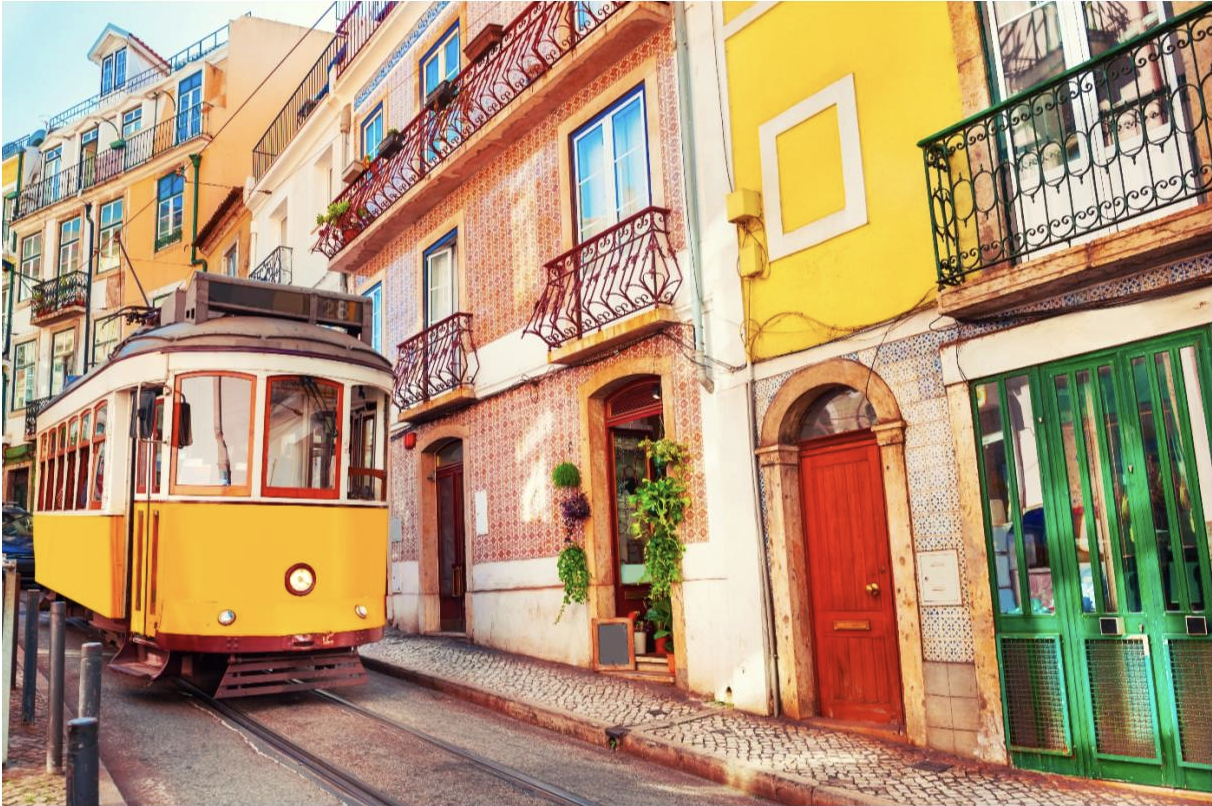 The yellow tram is traveling down Lisbon's colorful and narrow city streets