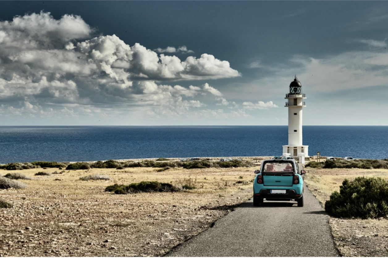 A car driving toward a lighthouse on an island in Spain