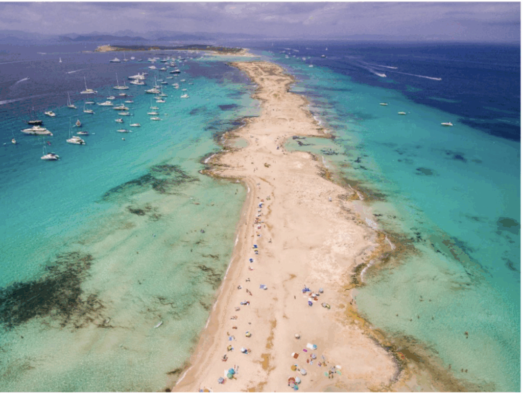 A thin stretch of beach between green ocean waters in Ibiza, one of the Balearic Islands
