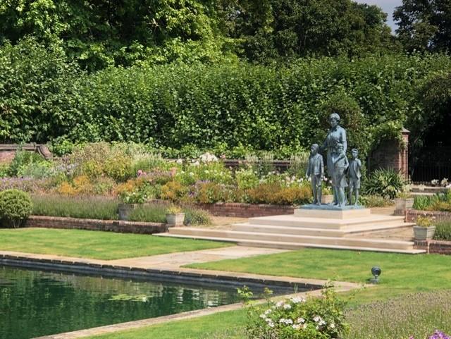 Princess Diana Memorial statue in Kensington Gardens sunken garden with children sculptures, reflecting pool, and lush greenery.