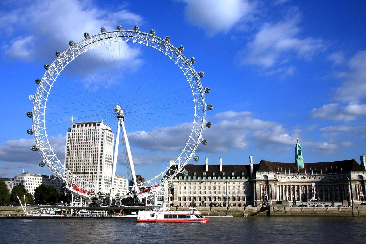 London Eye ferris wheel, one of the fun things to do with kids in London, overlooking River Thames with tour boat.