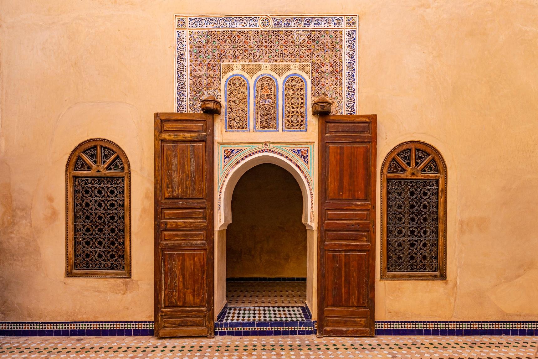 Ornate carved doorway in a luxury Moroccan riad, showcasing intricate tilework and timeless architectural elegance.